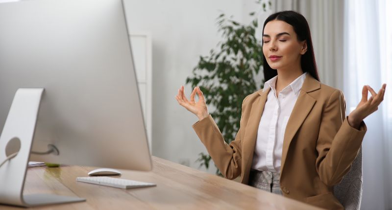 female worker practicing mediation at her desk